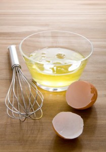 raw egg whites just cracked into a glass bowl waiting to be whisked