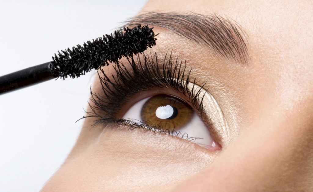 Woman applying mascara on eyelashes