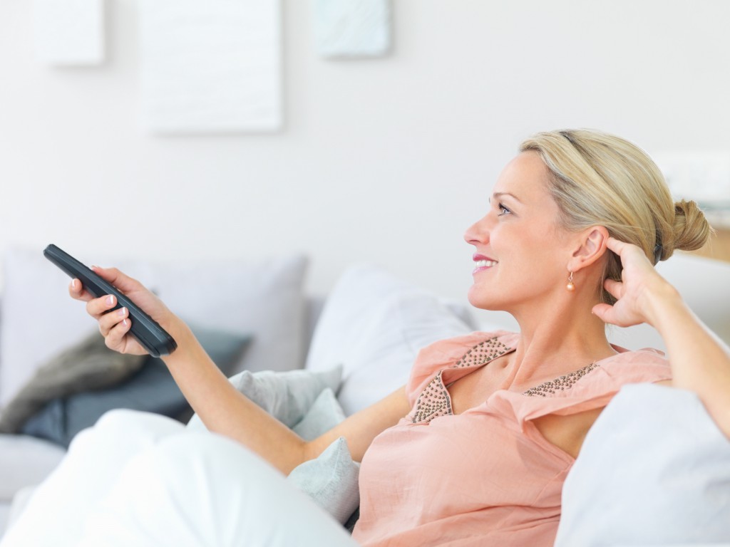 Pretty mature woman watching television while at home