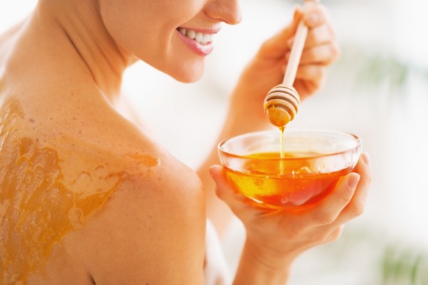 Closeup on young woman with honey on back holding honey plate