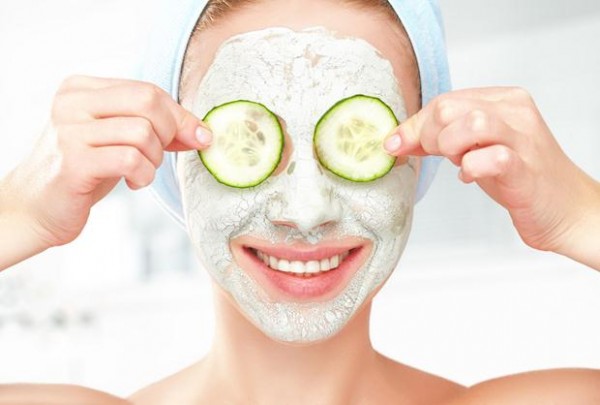 Funny young girl with a mask for skin face and cucumbers on eyes