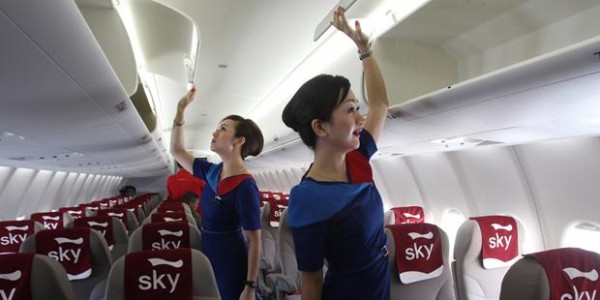 Sky Aviation's stewardesses shows to photographers the overhead luggage bin of a Sukhoi Superjet-100 during the unveiling ceremony of the first of the 12 jetliners purchased by the domestic airline at Halim Perdanakusumah airport in Jakarta, Indonesia, Thursday, Feb. 28, 2013. (AP Photo/Tatan Syuflana)