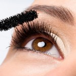 Woman applying mascara on eyelashes