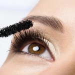 Woman applying mascara on her eyelashes – macro shot