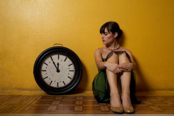 Woman sitting on floor by large antique clock
