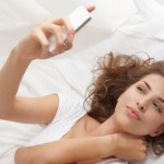 Woman using cell phone on bed