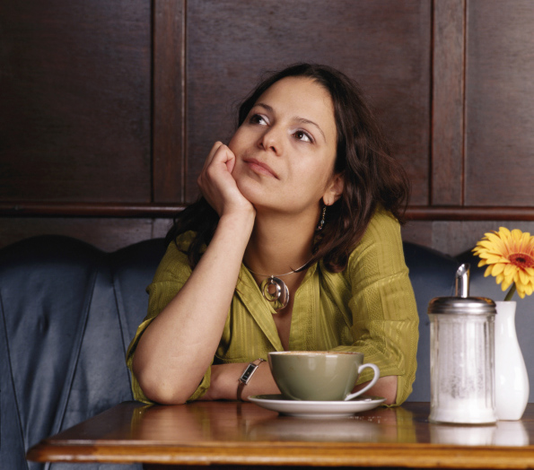 Woman sitting in cafe, chin on hand
