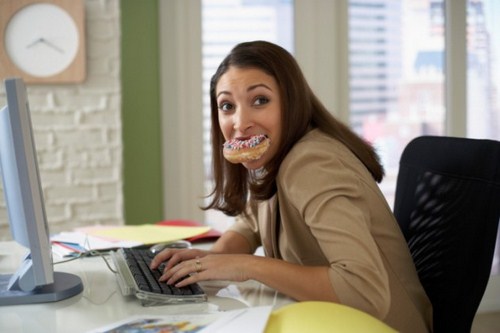 Woman-eating-a-donut-at-her-computer-78715216-Credit-Fuse-630x420