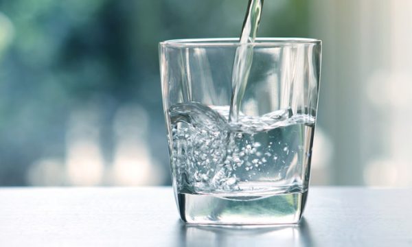 Close up the  pouring purified fresh drink water from the bottle on table in living room